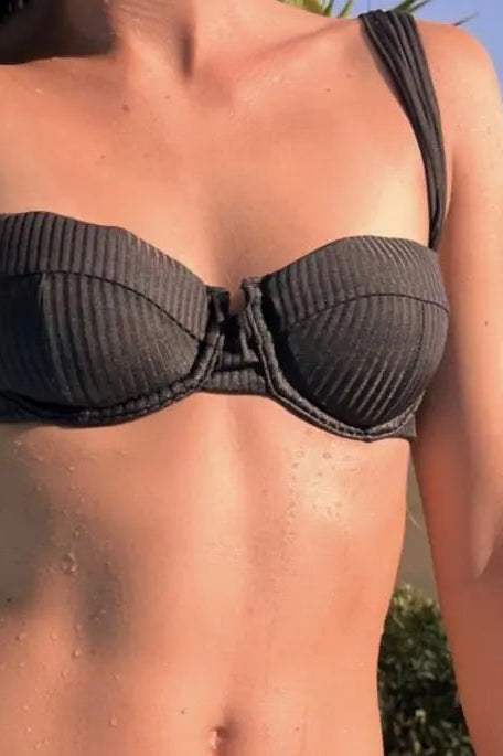 Person wearing a black bikini set with a blurred outdoor background